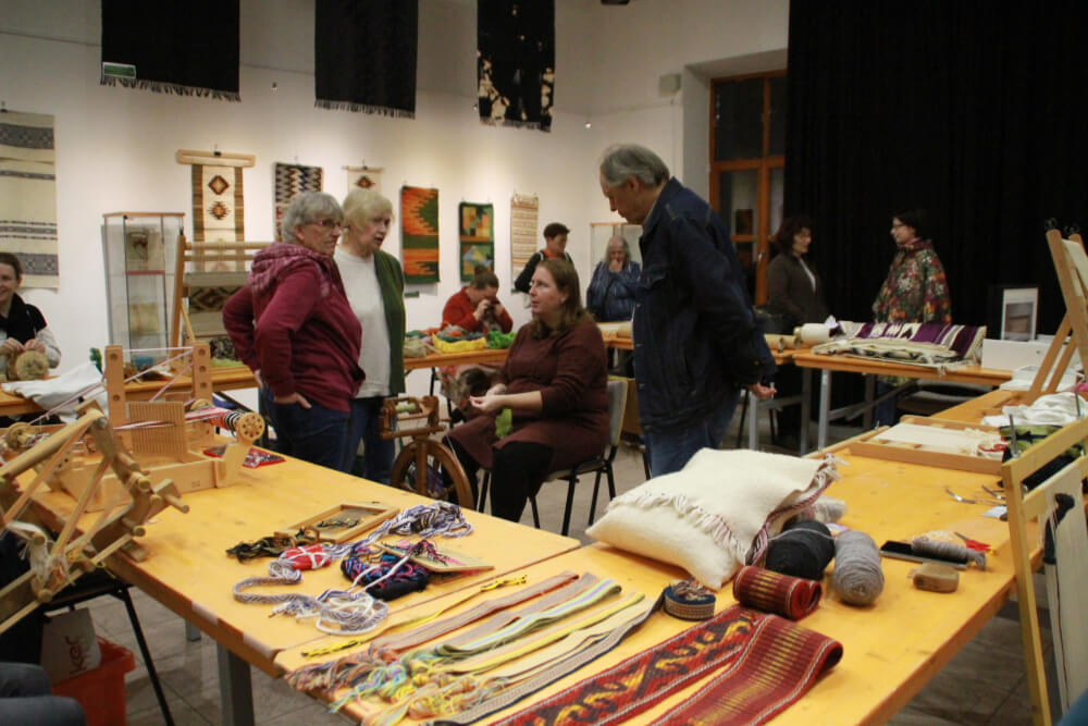 Szövőszakkör résztvevői, a falon és az asztalon szövésekkel.